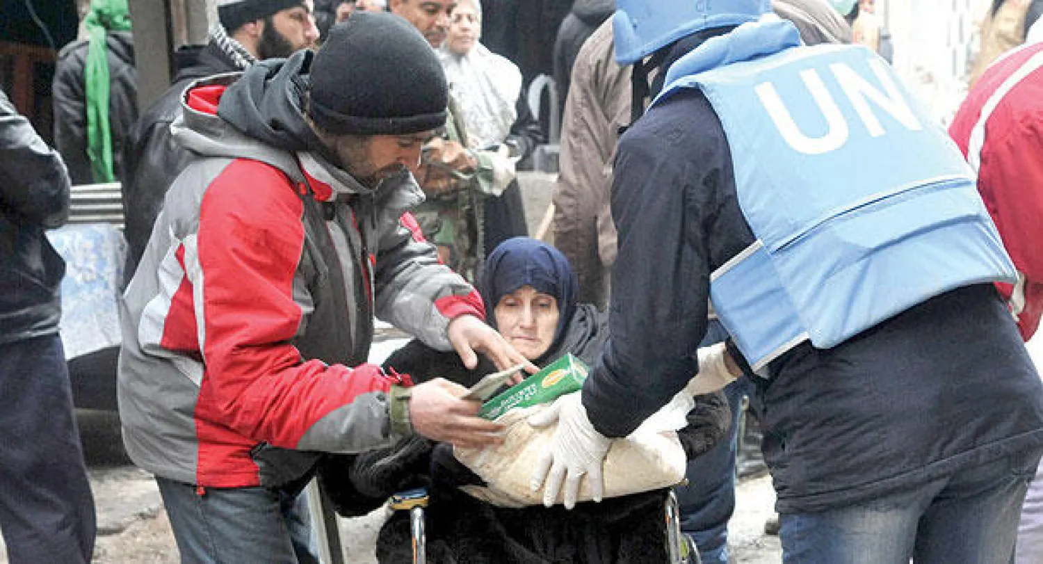 مساعدات غذائية من «الأونروا» توزع على سكان مخيم اليرموك جنوب دمشق أمس (رويترز)