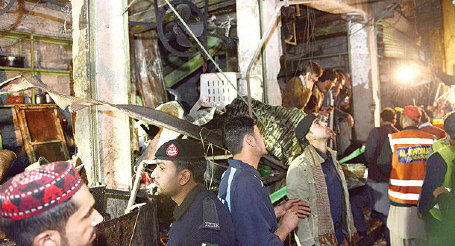 عناصر من الأمن ومواطنون يتجمعون أمام موقع التفجير الانتحاري في بيشاور أمس (أ.ف.ب)