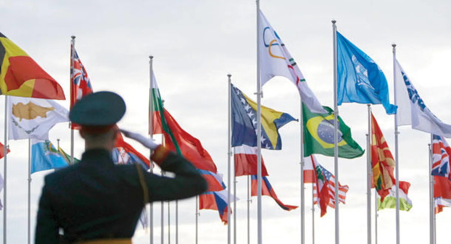 شرطي روسي يحيي العلم أثناء احتفال ترحيبي بفرق مشاركة في الدورة (رويترز)