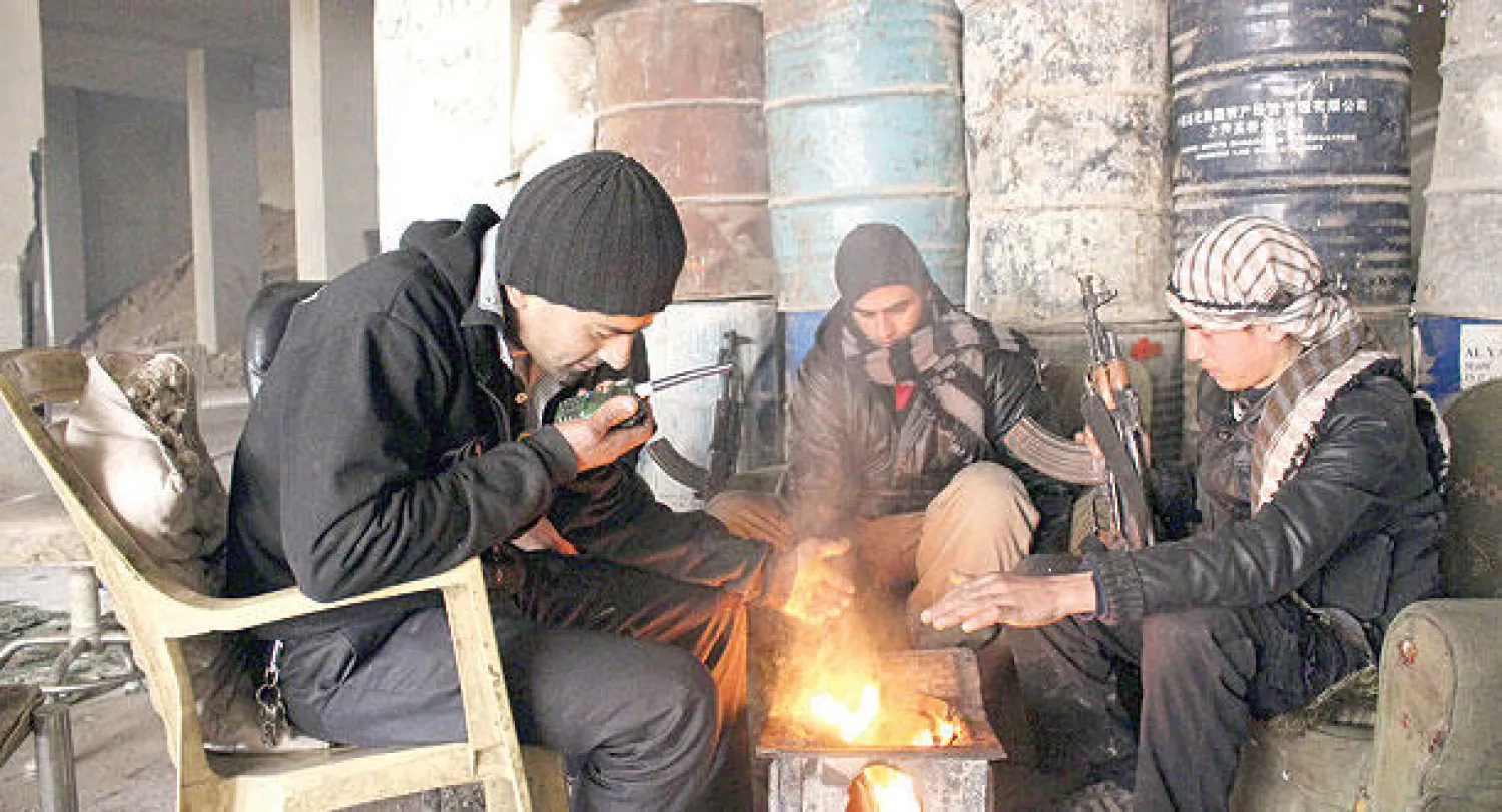 مقاتلون متجمعون حول نار أوقدوها كي تقيهم البرد في الغوطة قرب دمشق (رويترز)