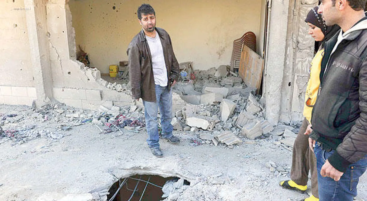 لبنانيون يعاينون منزلا في عرسال أصابته قذيفة أطلقت من الجانب السوري (رويترز)