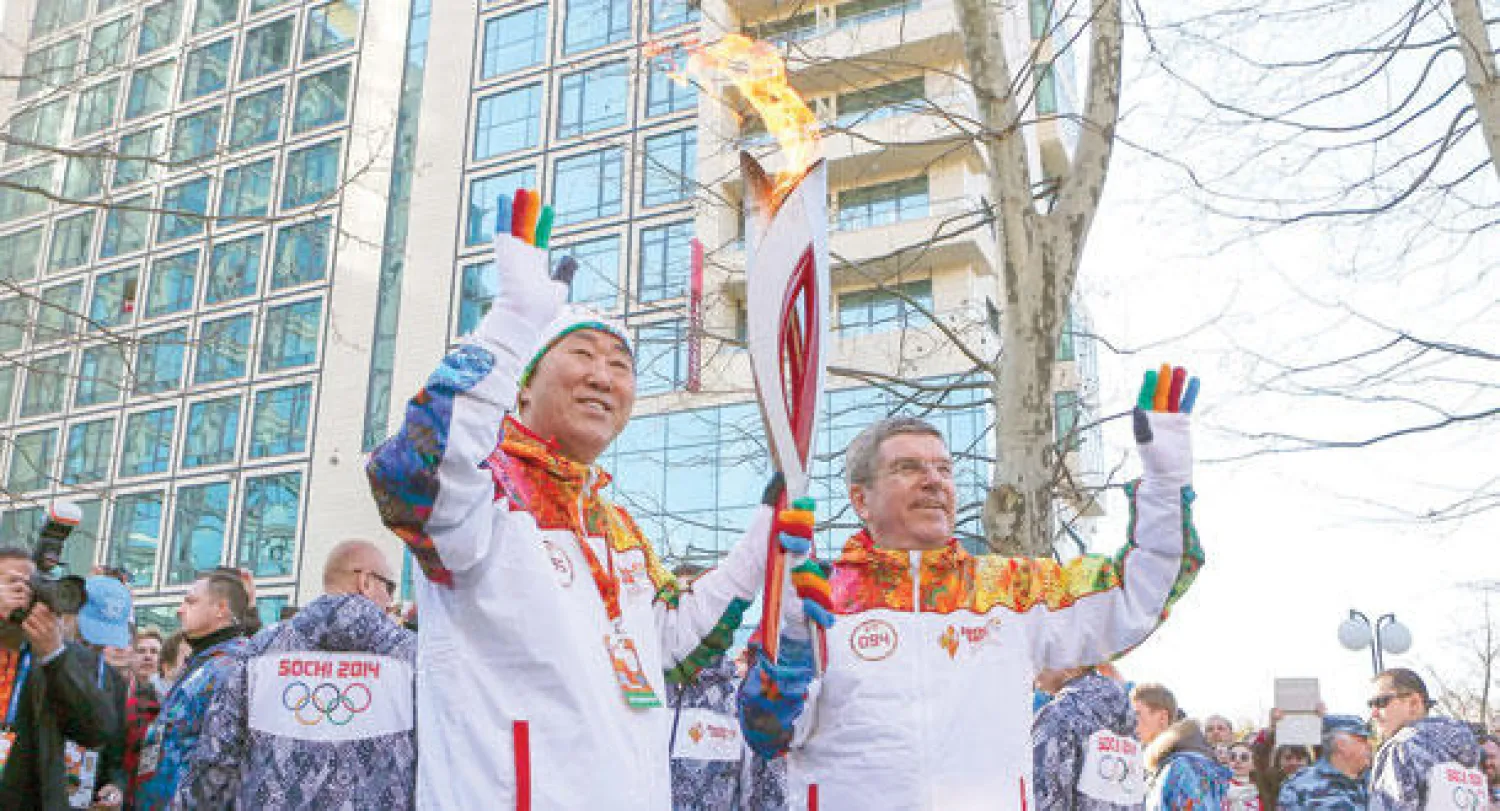 رئيس اللجنة الأولمبية الدولية توماس باخ يسلم الشعلة الأولمبية لأمين عام الأمم المتحدة بان كي مون في سوتشي أمس (رويترز)