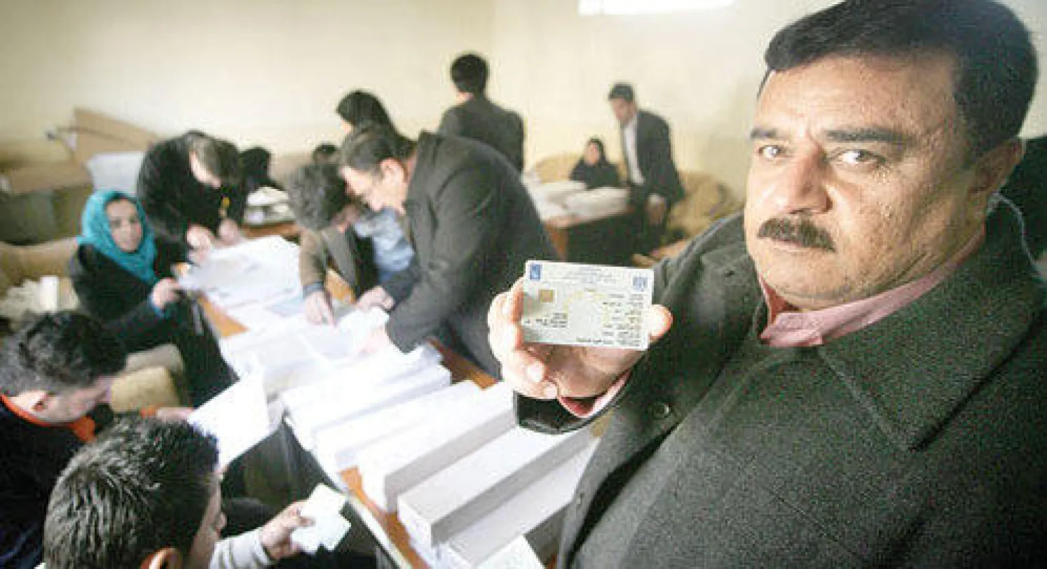كردي عراقي يتسلم بطاقته الانتخابية الإلكترونية في أحد مراكز أربيل، أمس (أ.ف.ب)