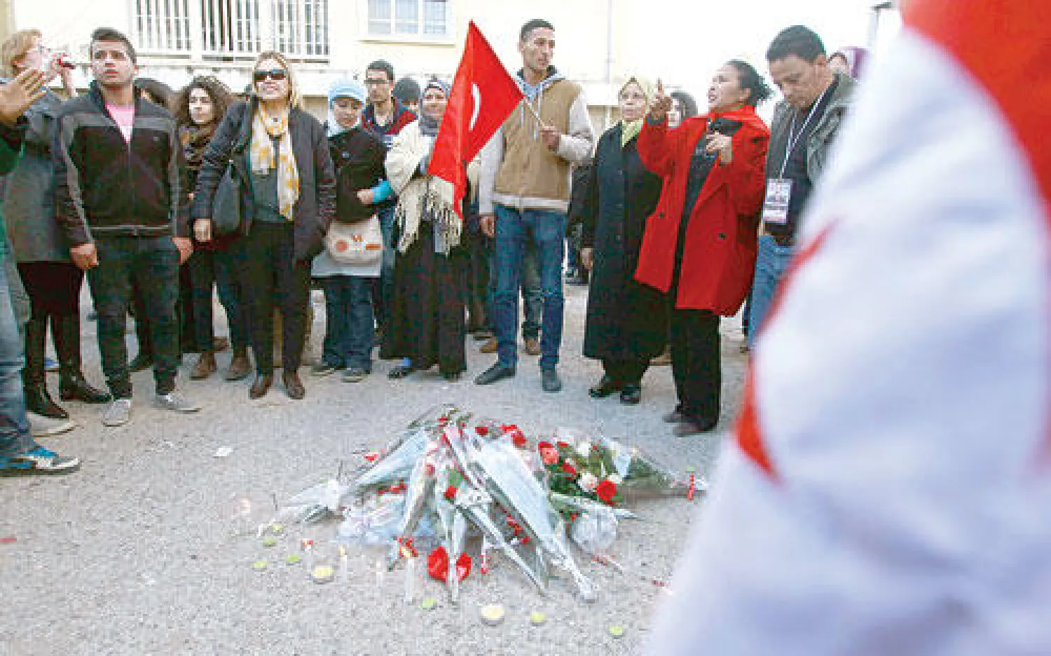 تونسيون يجتمعون حول باقات من الورود بمناسبة الذكرى الأولى لاغتيال شكري بلعيد أمام بيته في تونس أمس (رويترز)