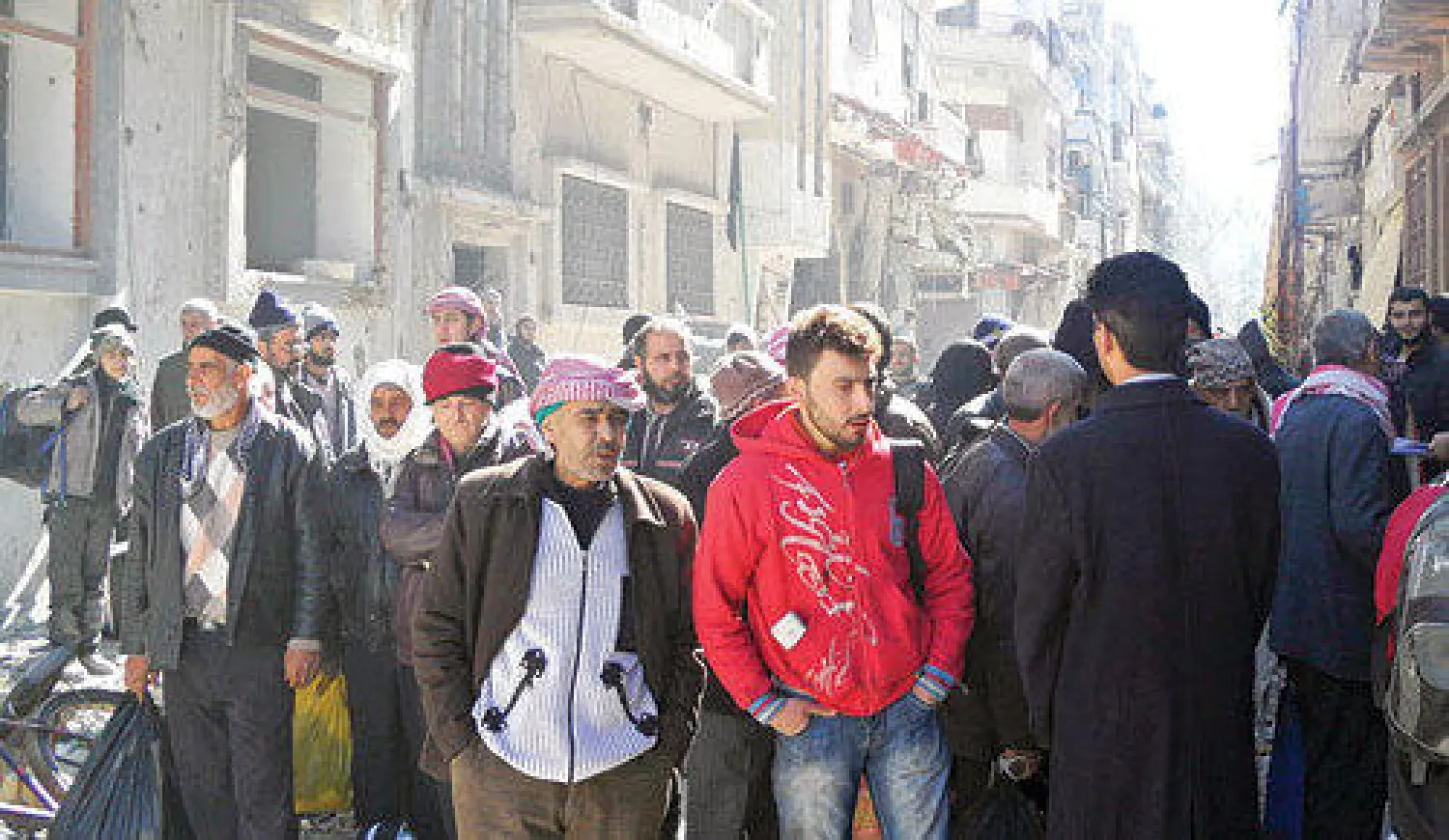 سوريون في انتظار ترحيلهم إلى خارج المناطق المحاصرة في حمص أمس (رويترز)