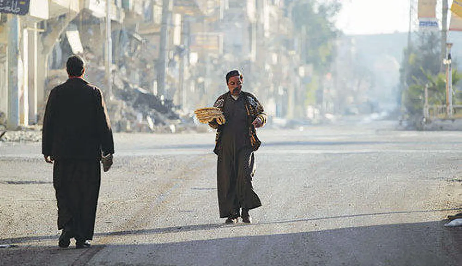 مواطن سوري يسير أمس بين ركام المباني في دير الزور التي تتعرض دائما لقصف متواصل (رويترز)