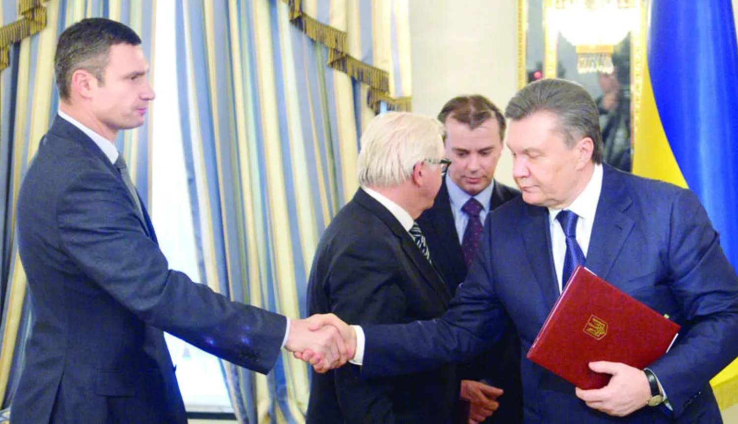 الرئيس يانوكوفيتش (يمين) يصافح الزعيم المعارض فيتالي كلتشكو بعد توقيع اتفاق السلام في كييف أمس (أ.ف.ب)