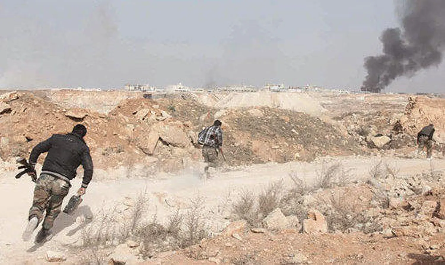 مقاتلون يبحثون عن ملجأ للاختباء خلال معارك في حي شيخ نجار بضواحي حلب أمس (أ.ف.ب)