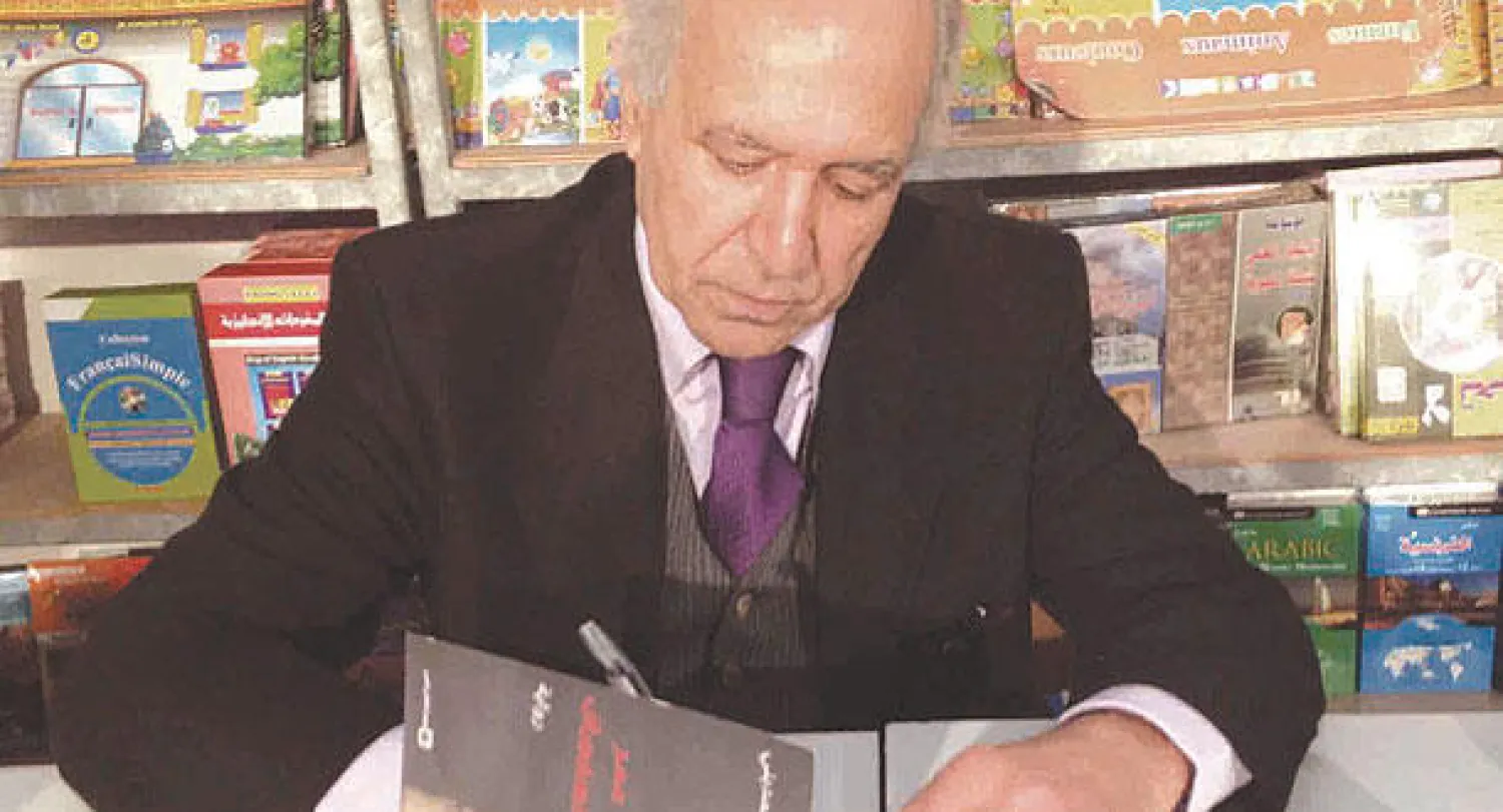 الكاتب المغربي أحمد المديني أثناء توقيع روايته الجديدة للقراء («الشرق الأوسط»)