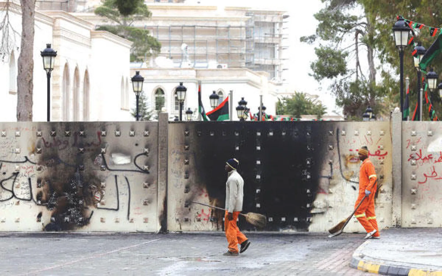 عاملان أمام مقر المؤتمر الوطني الليبي الذي اقتحمه أمس متظاهرون غاضبون في طرابلس عقب فض اعتصام من محيطه أول من أمس (أ.ف.ب)