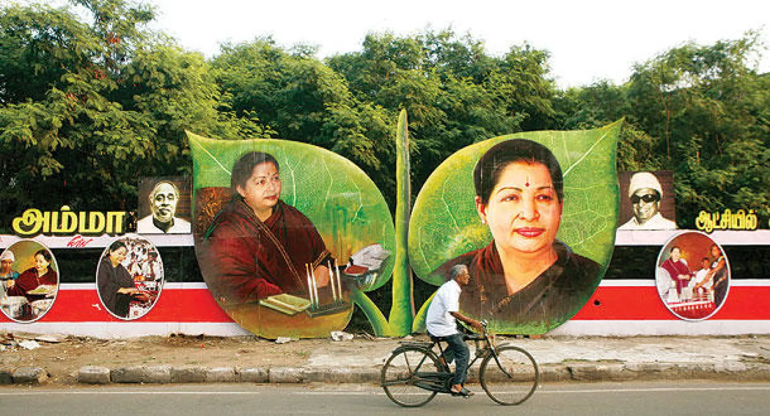 رجل يمر بدراجته أمام صورتين انتخابيتين لرئيسة حكومة ولاية تاميل نادو الهندية، جايارام جايالاليتا،  داخل إطارين على شكل ورقتين، في مدينة شيناي أمس (أ.ب)