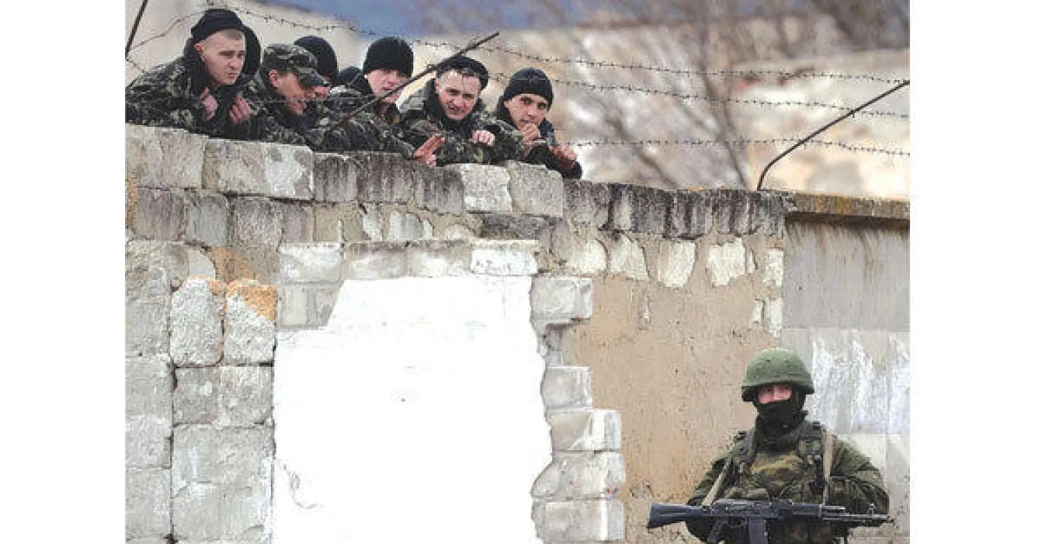 جندي روسي ومجموعة من قوات المظلات في إحدى القواعد الروسية على الحدود الأوكرانية أمس (أ. ف. ب)