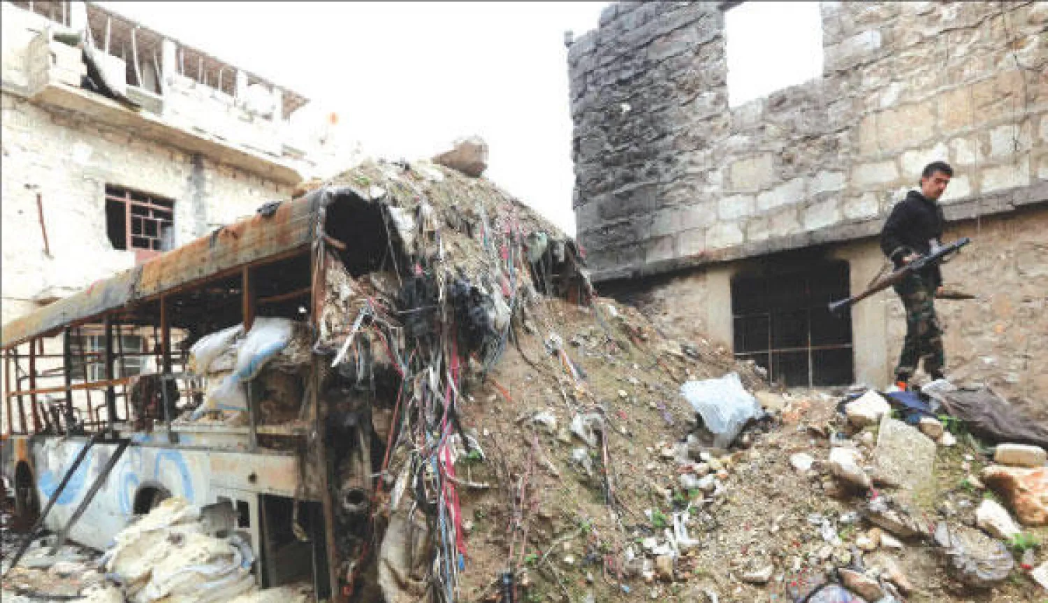 مقاتل من الجيش السوري الحر يمر فوق ركام مبنى في منطقة الأشرفية بحلب أمس (رويترز)
