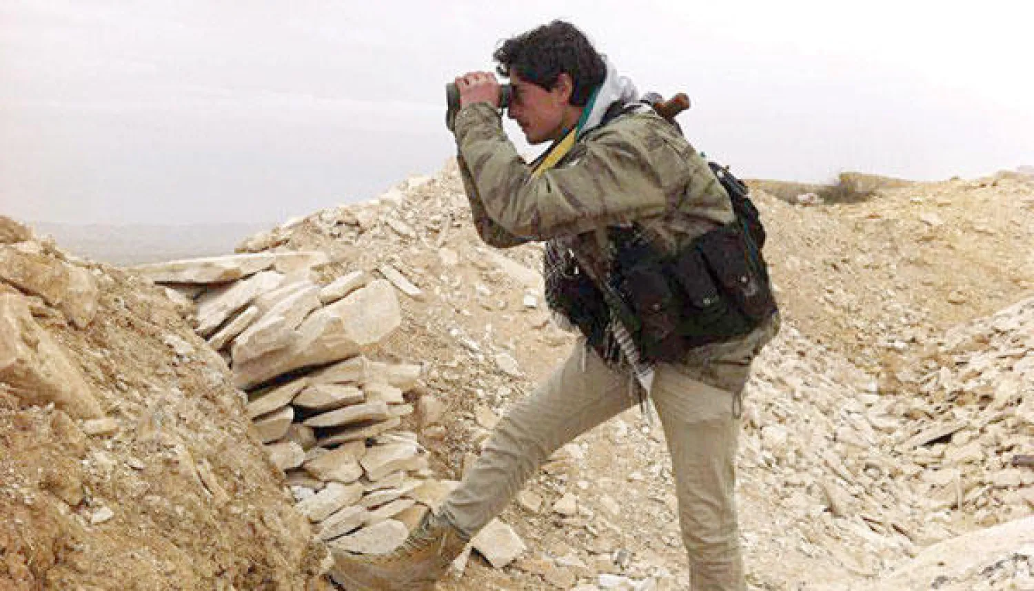 ناشط سوري يرصد تحركات جيش النظام ومسلحي حزب الله عند أحد خطوط المواجهة في يبرود أول من أمس (أ.ب)