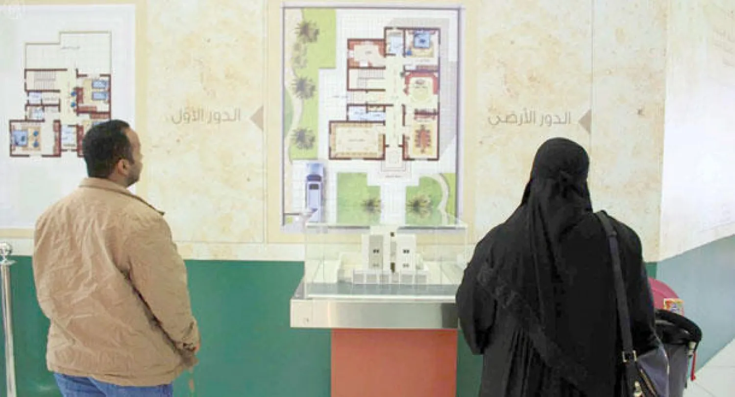 سيدة ورجل يطالعان مخططات أحد مشاريع الإسكان الحكومية في جناح وزارة الإسكان بمهرجان الجنادرية (واس)