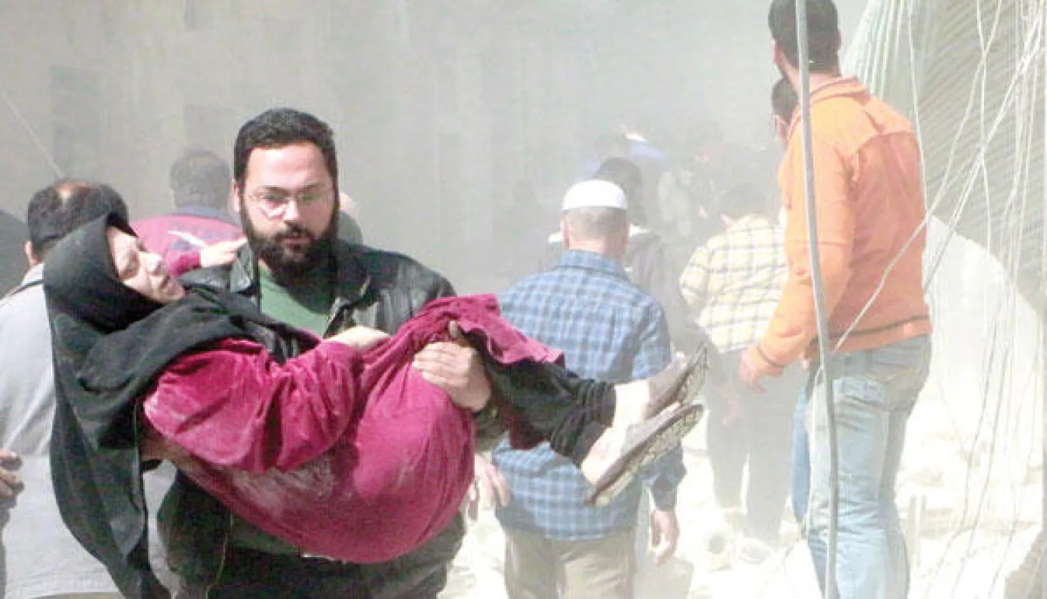 سوري يساعد امرأة أصيبت في قصف جوي بمدينة حلب أمس (أ.ف.ب)