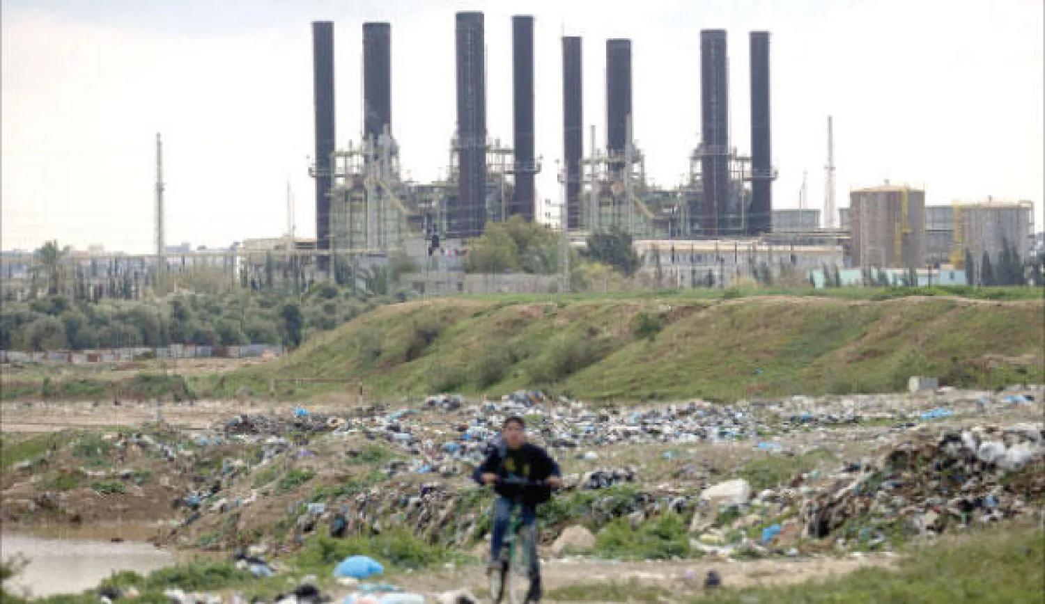 صبي فلسطيني يمر على دراجته بمحطة الكهرباء الوحيدة والرئيسة في غزة أمس (أ.ف.ب)