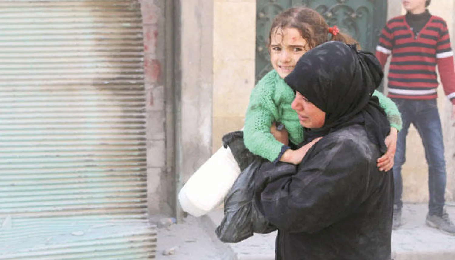 سورية تحمل طفلة أصيبت في قصف جوي على حلب أمس (رويترز)