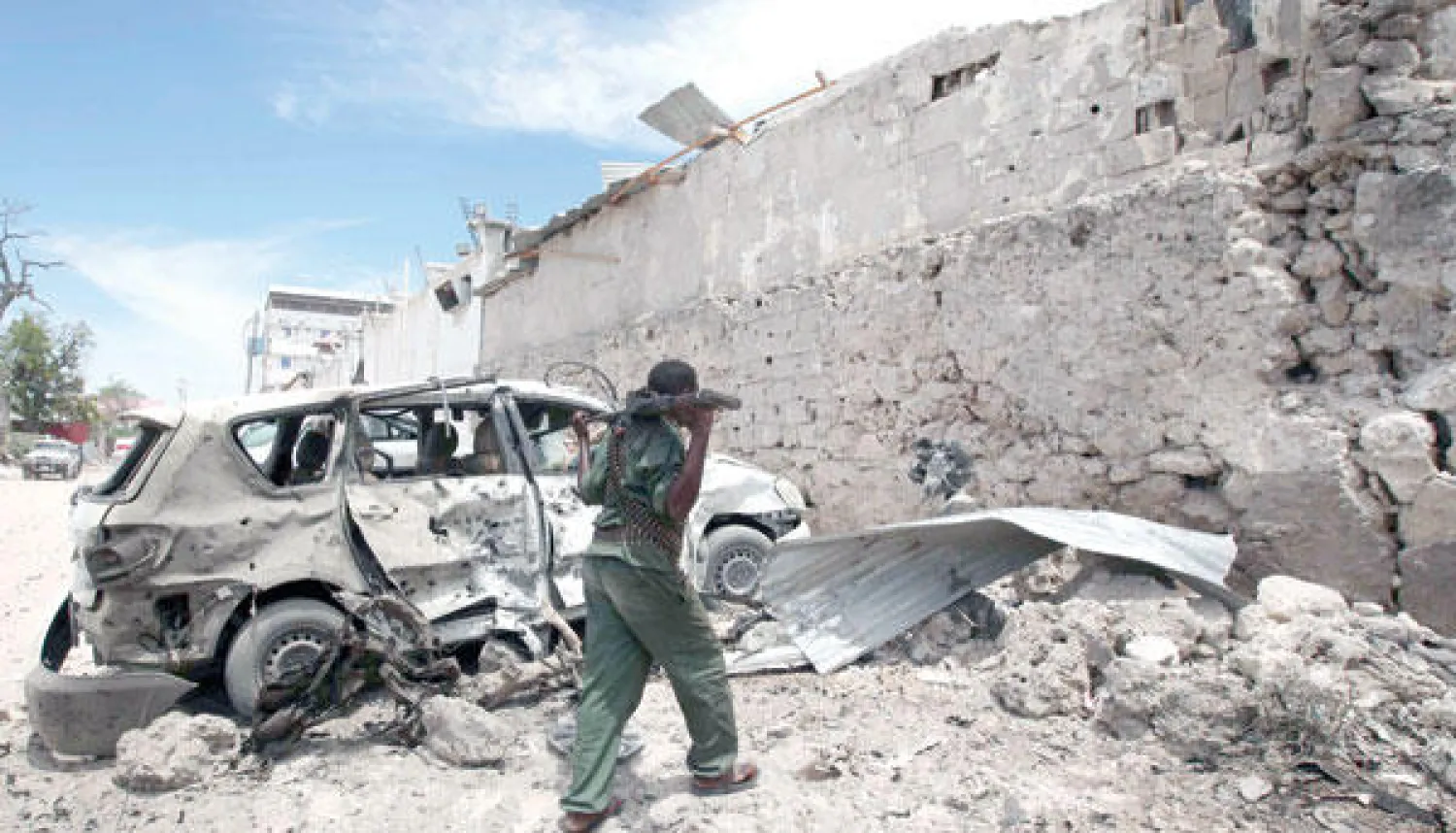 جندي اصومالي يمشي بجانب سيارة تضررت من الانفجار في مقديشو أمس (رويترز)