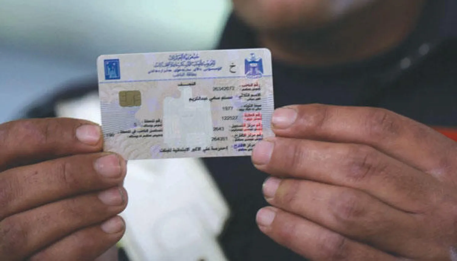 عنصر أمن عراقي يعاين بطاقته الانتخابية الإلكترونية بعد أن تسلمها من مكتب مفوضية الانتخابات في النجف (أ.ف.ب)