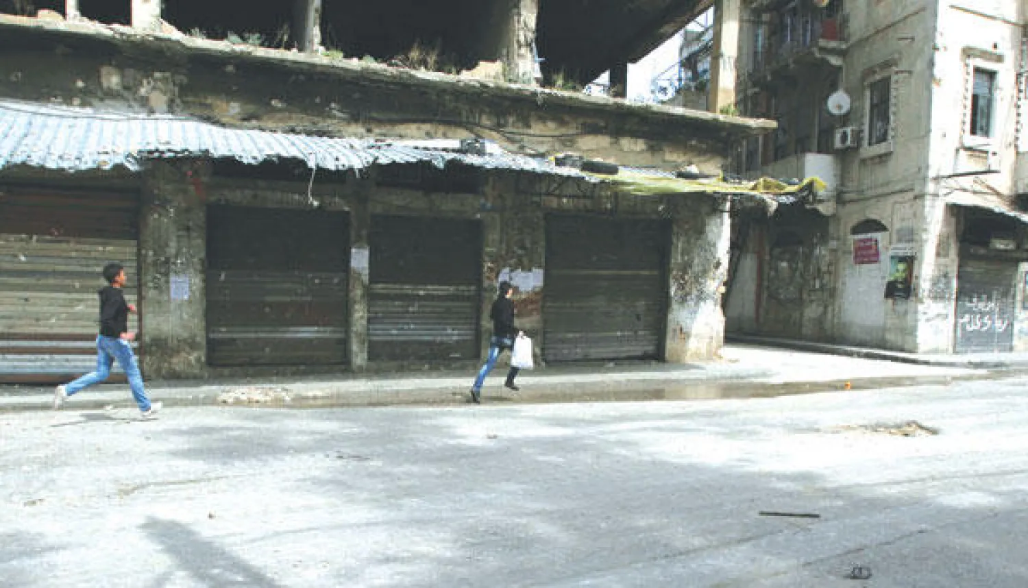 لبنانيان يفران من نيران القناصة في حي باب التبانة بطرابلس أمس (رويترز)