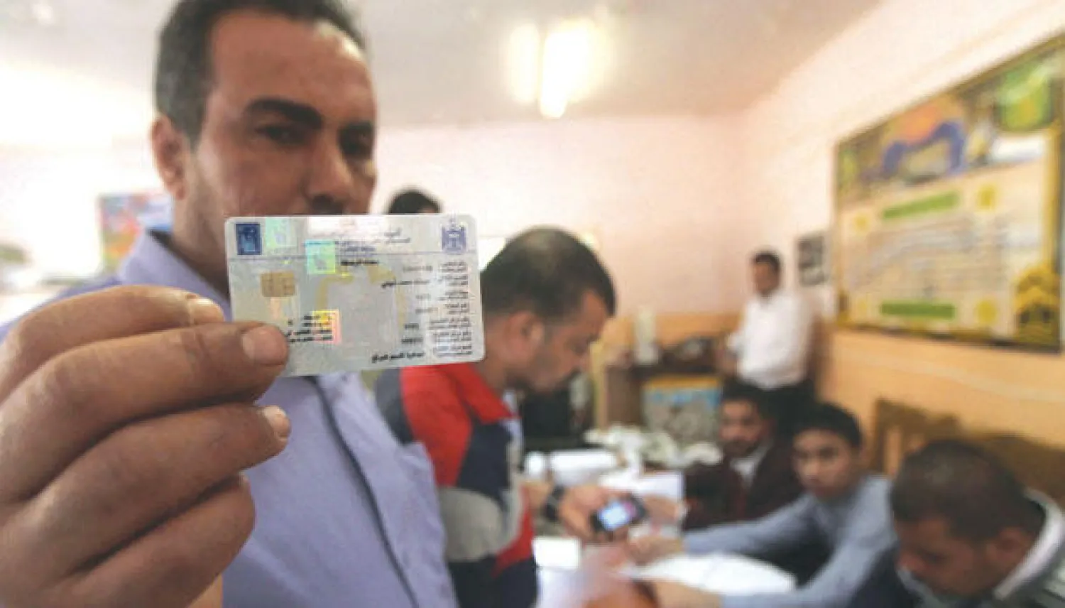 عراقي يرفع بطاقته الانتخابية الإلكترونية بعد استلامها من مكتب لمفوضية الانتخابات في بغداد مؤخرا (أ.ف.ب)