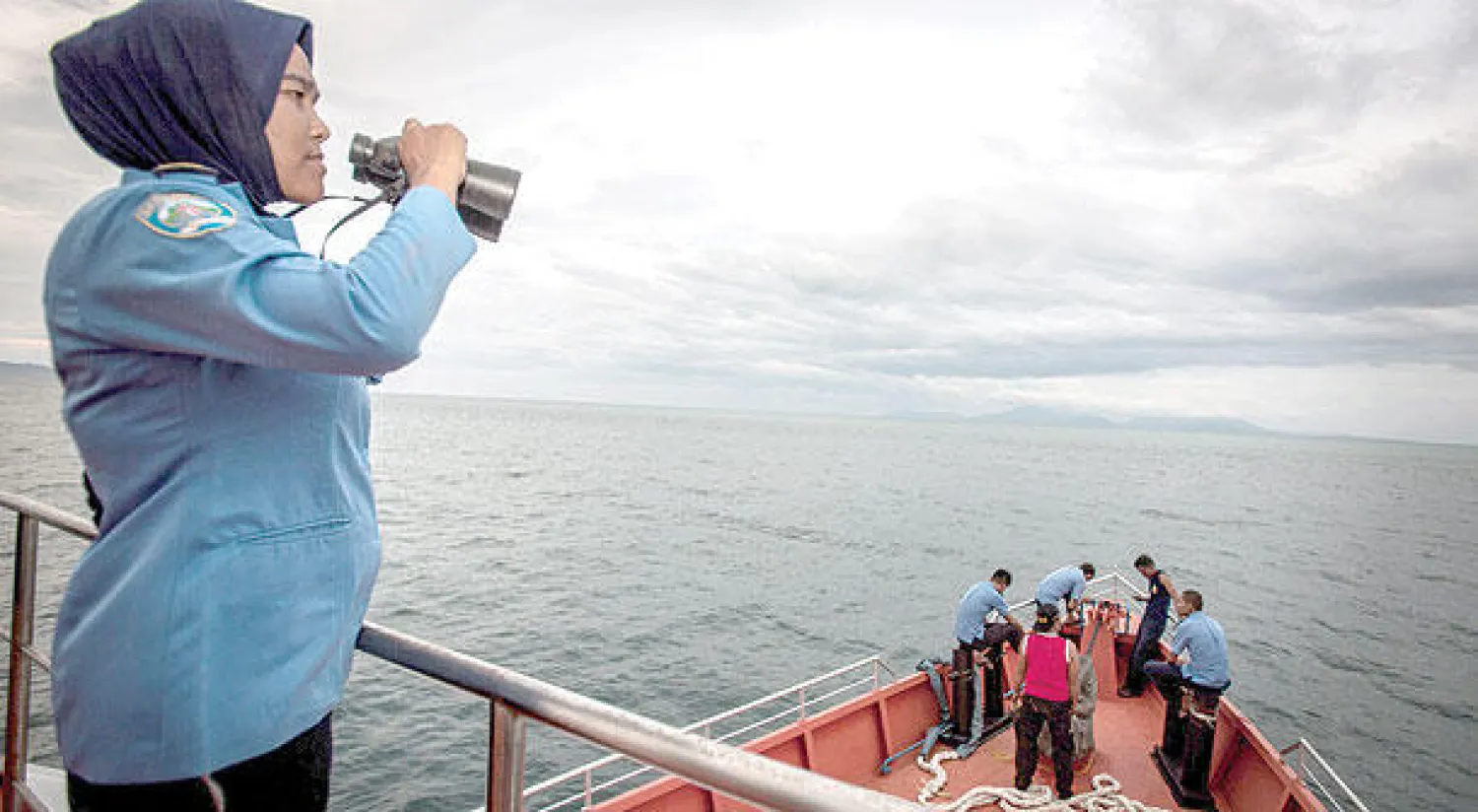 امرأة ضمن الفريق الإندونيسي المكلف البحث عن الطائرة المفقودة، تنظر في الأفق  من فوق متن سفينة قبالة سواحل جزيرة سومطرة أمس (أ.ف.ب)