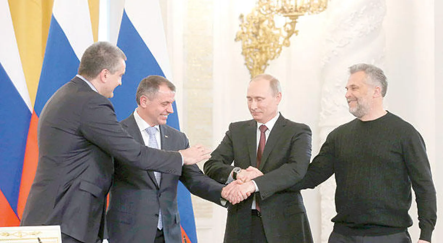 بوتين (الثاني يمينا) يصافح رئيس برلمان القرم فلاديمير كونستانتينوف (الثاني يسارا) ورئيس وزراء القرم سيرغي أكسيونوف (يسار) وعمدة سيفاستوبول أليكسي شاليي، بعد توقيع اتفاقية ضم شبه الجزيرة إلى روسيا، في الكرملين أمس (أ.ب)