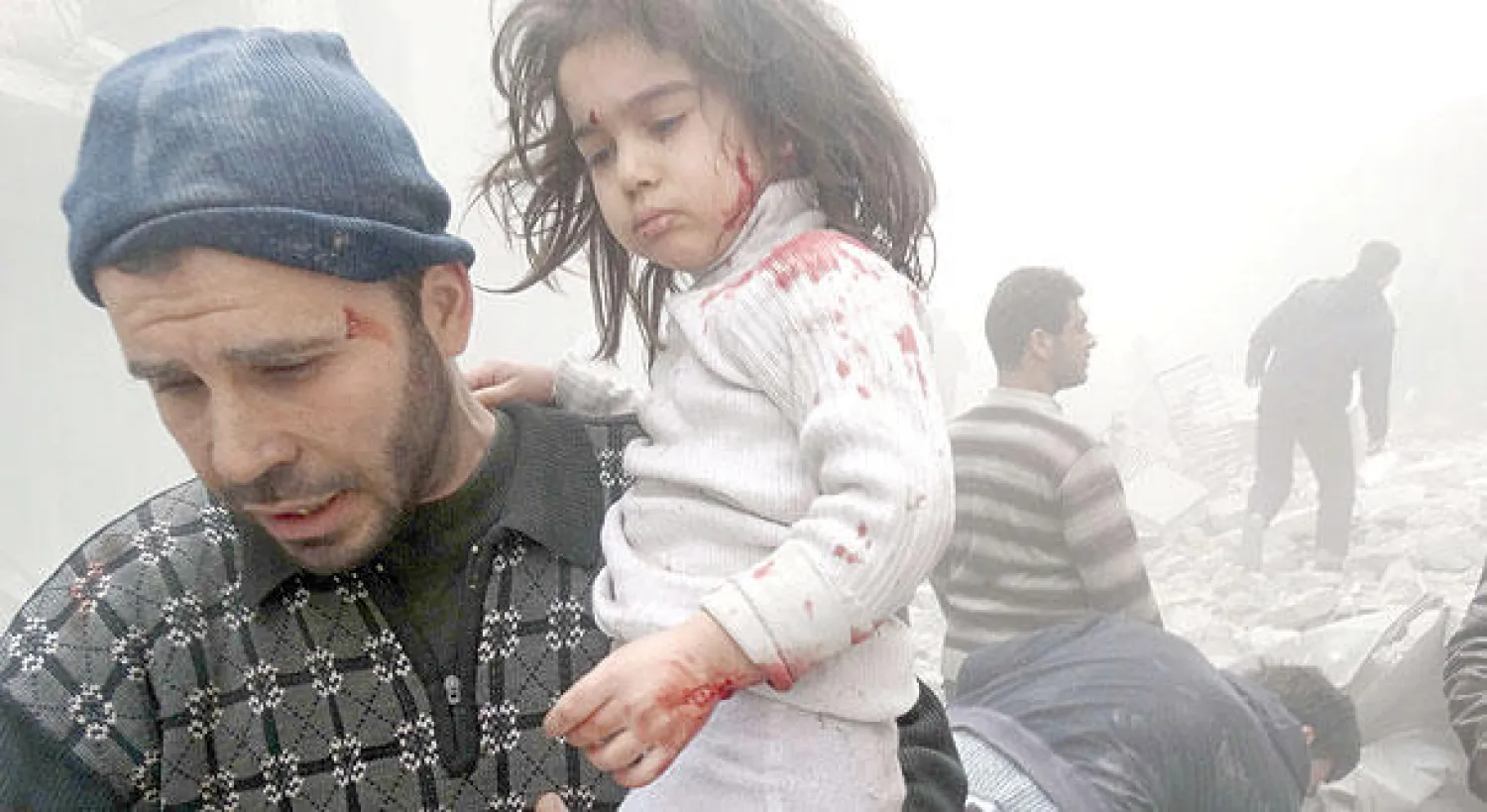 سوري يبعد طفلة عن مبنى بعد انهياره إثر استهدافه ببرميل متفجر في حلب أمس (أ.ف.ب)