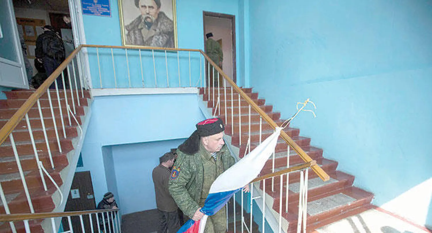 رجل موال لروسيا يحمل علمها لرفعه بدل العلم الأوكراني فوق المقر الرئيسي للبحرية في مدينة سيفاستوبول بالقرم أمس (رويترز)