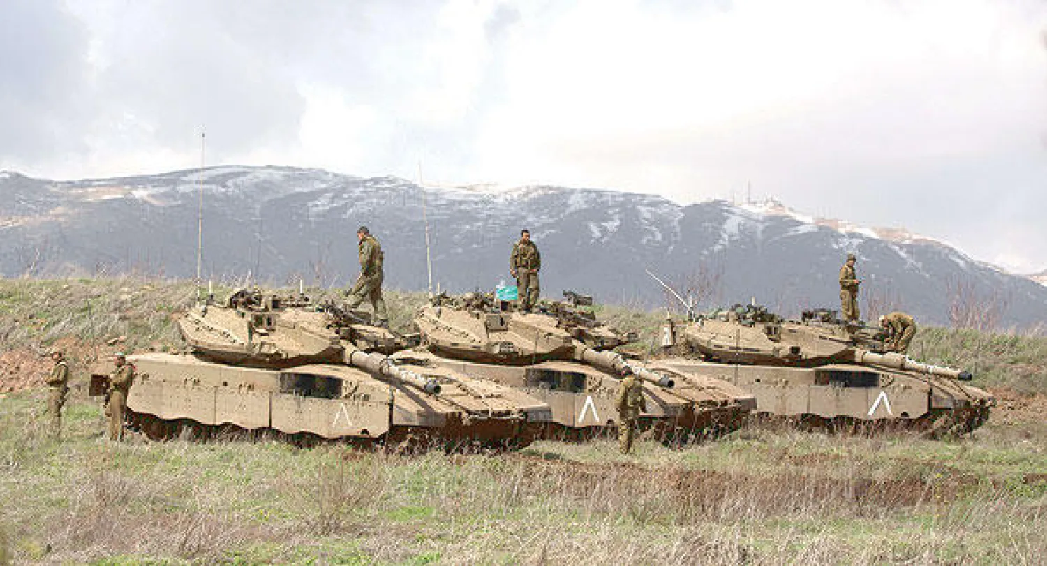 جنود إسرائيليون يقفون على ظهور دباباتهم في الجولان  قرب قرية مجدل شمس الدرزية السورية أمس (أ.ف.ب)