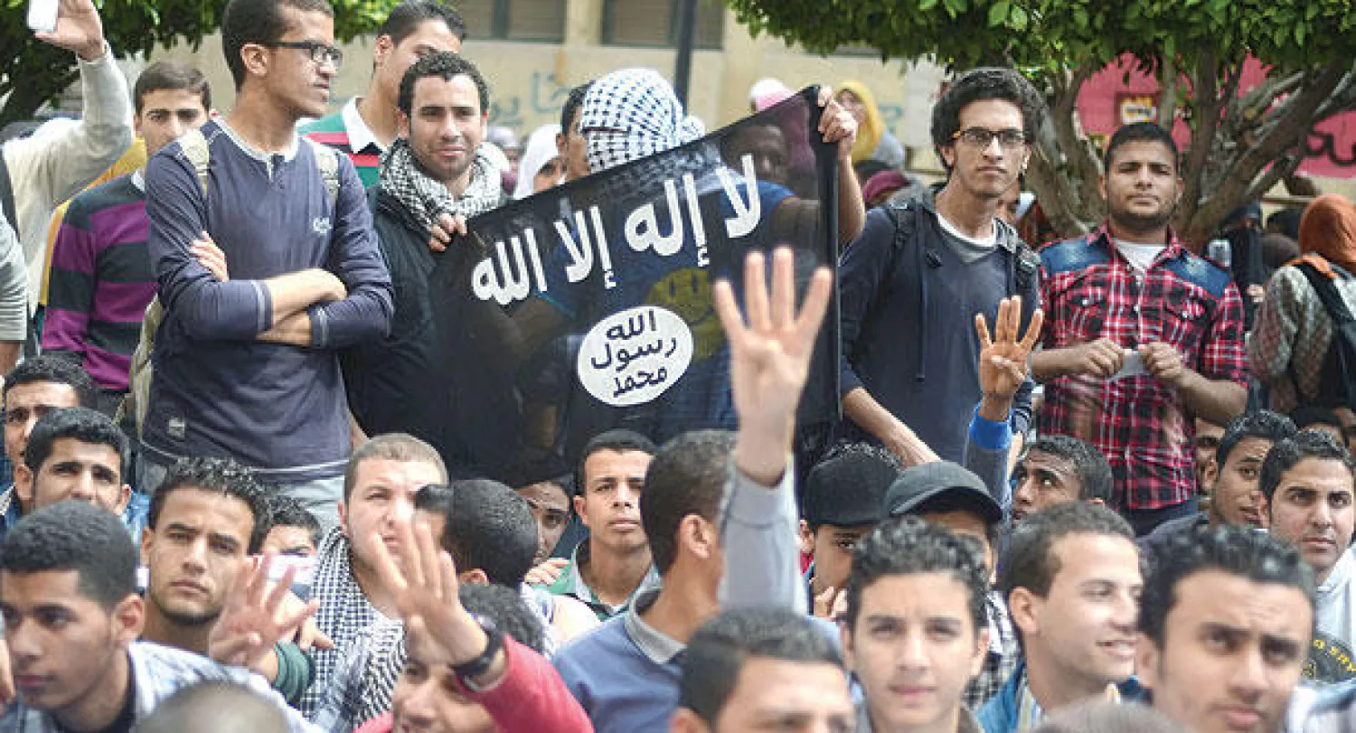 طلاب مناصرون لجماعة «الإخوان» يرفعون شعار «رابعة» وعلما لـ«القاعدة» خلال تظاهرهم في جامعة القاهرة أمس (أ.ف.ب)