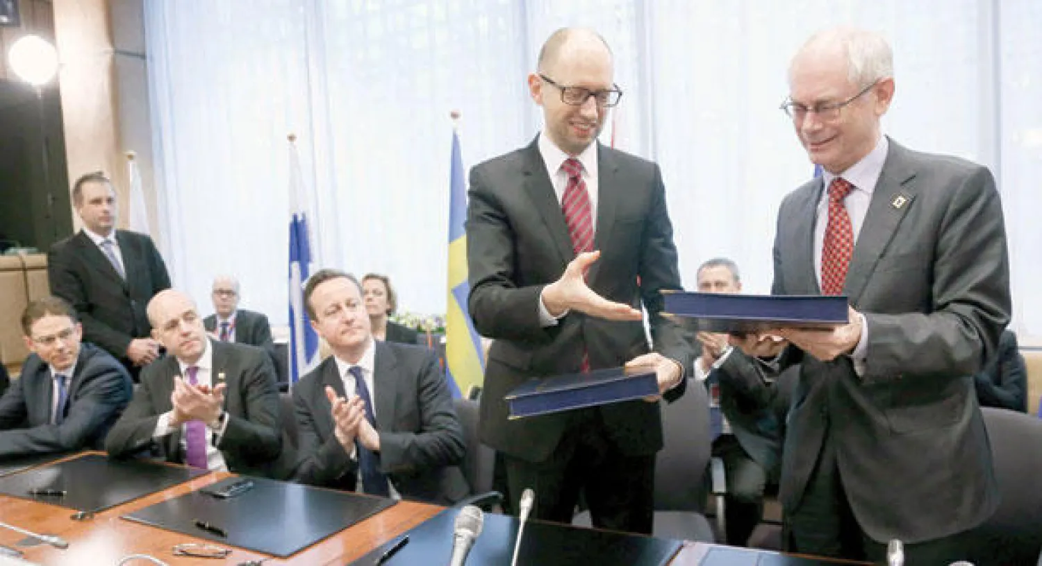 رئيس المجلس الأوروبي هيرمان فان رومبوي (يمين) ورئيس الوزراء الأوكراني آرسيني ياتسينيوك يتبادلان الوثائق خلال حفل توقيع اتفاق الشراكة في بروكسل أمس (إ.ب.أ)