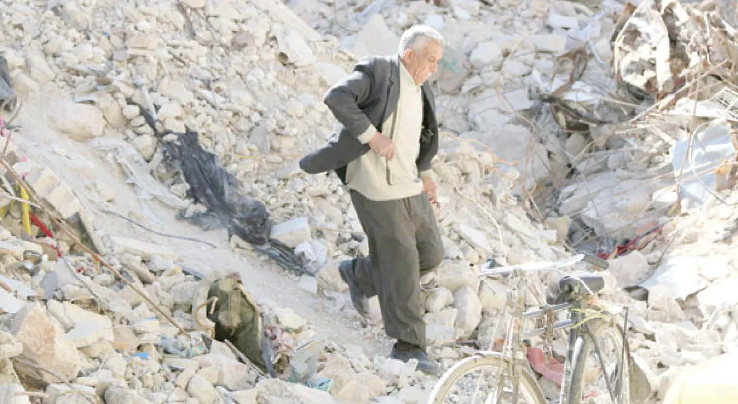 سوري يسرع نحو دراجته الهوائية فوق حطام بنايات إثر قصف النظام لها بالبراميل المتفجرة بحلب أمس (رويترز)