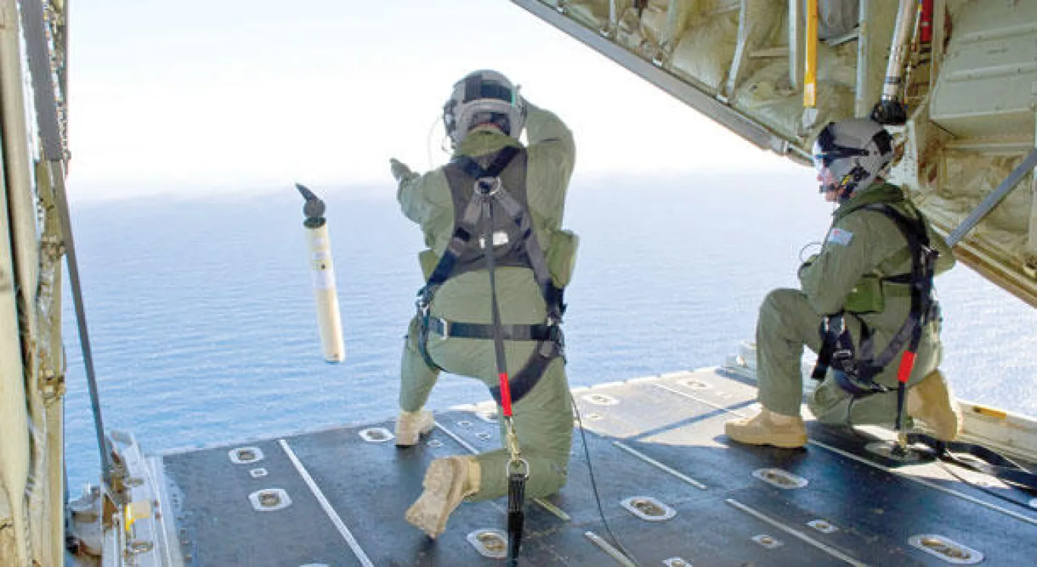 ضابطان في البحرية الأسترالية يطلقان من على متن سفينة جهازا لتحديد المواقع داخل الماء في جنوب المحيط الهندي في إطار البحث عن الحطام المحتمل للطائرة (أ.ف.ب)