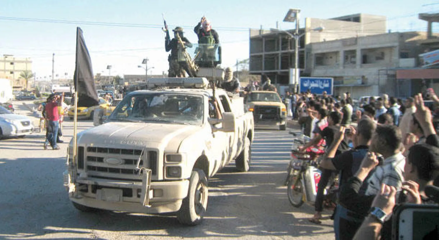 مقاتلون من تنظيم القاعدة يسيطرون على سيارات تابعة للقوات الأمنية العراقية ويرفعون عليها علم تنظيمهم وسط الفلوجة أول من أمس (رويترز)