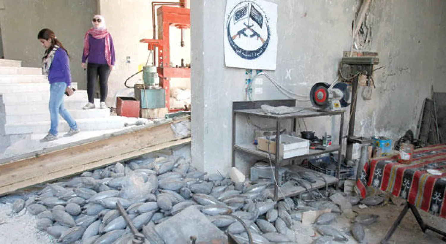 سوريتان تمران إلى جانب مصنع للسلاح تابع للجيش السوري الحر في يبرود بريف دمشق أمس (رويترز)