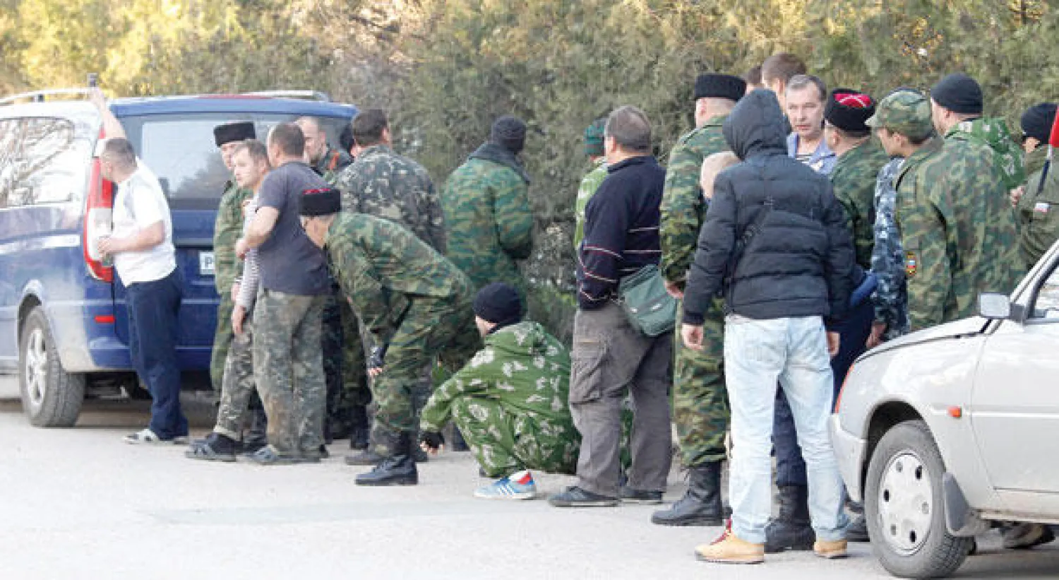 عناصر موالية لروسيا تراقب الوضع خارج قاعدة عسكرية جرى اقتحامها وطرد جنود أوكرانيين منها قرب مدينة سيفاستوبول بالقرم أمس (رويترز)