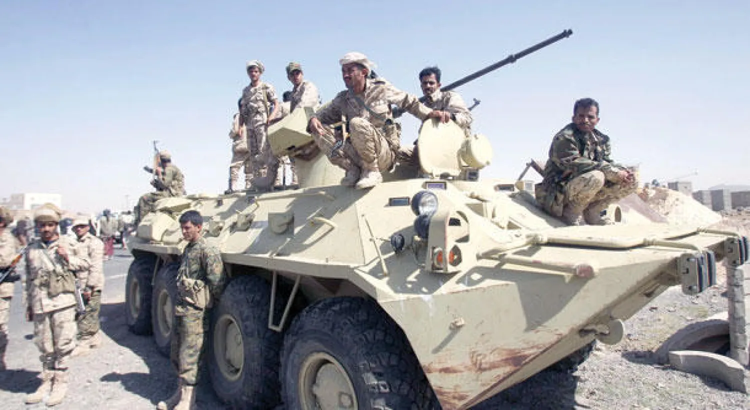 جنود يمنيون يجلسون فوق ناقلة جنود بالقرب من مؤيدين لجماعة الحوثيين شرق العاصمة صنعاء أمس (رويترز)