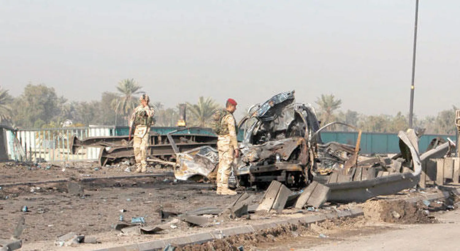 جنديان عراقيان يتفحصان سيارة انفجرت فوق جسر المثنى شمال بغداد وخربت جزءا منه (رويترز)
