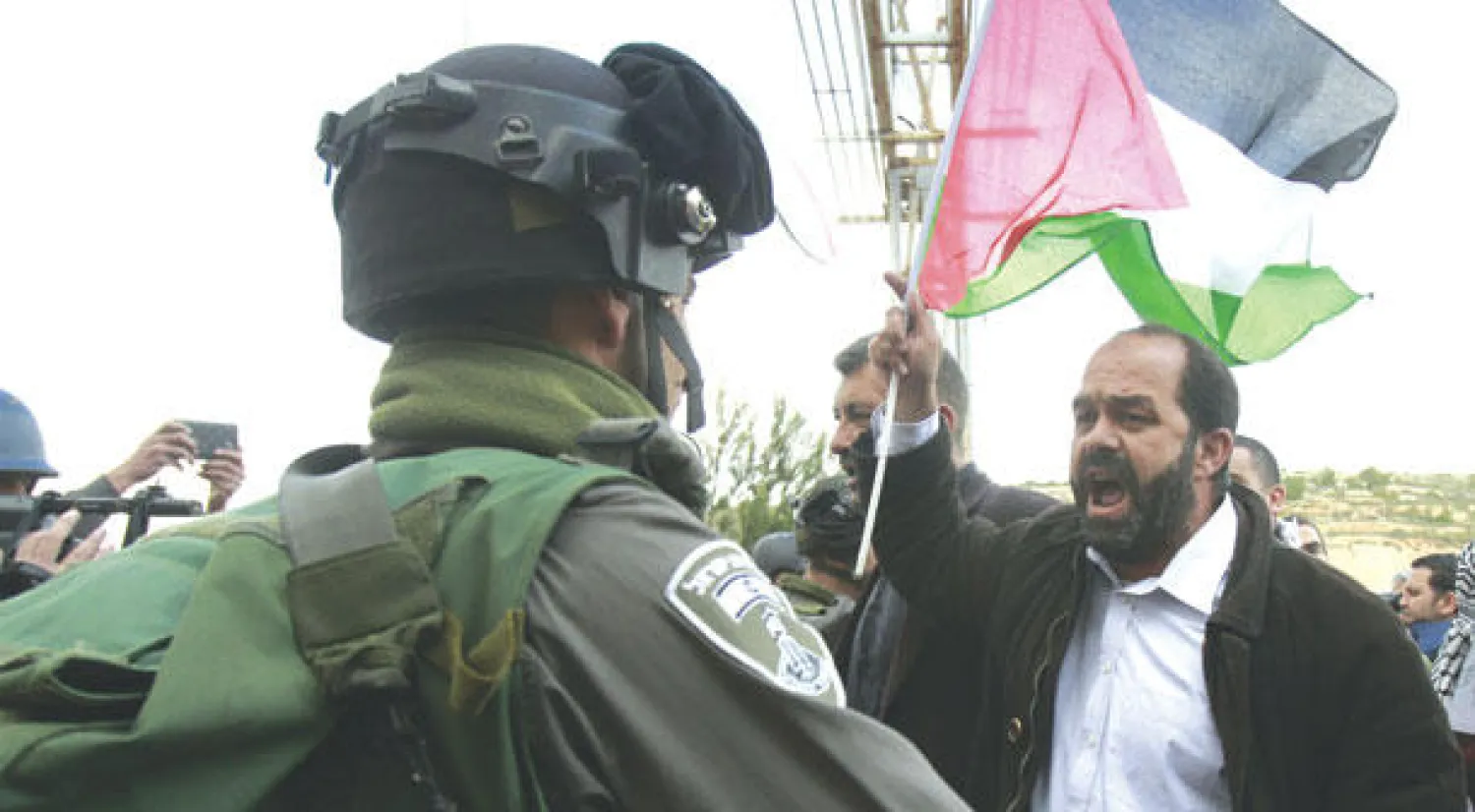 جندي إسرائيلي يراقب فلسطينيا يردد شعارات خلال مظاهرة بمناسبة يوم الأرض في قرية الخضر قرب بيت لحم أمس (أ.ف.ب)