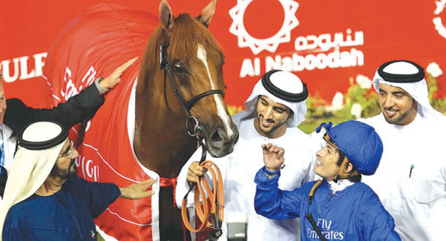 الشيخ محمد بن راشد ونجله حمدان مع الحصان «أفريكان ستوري» الفائز بكأس دبي للخيول (أ.ب)