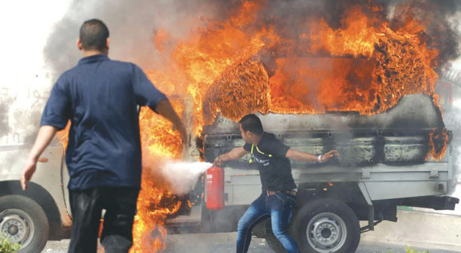 رجال شرطة في زي مدني يحاولون إطفاء سيارة عقب إضرام النيران فيها من قبل طلاب في جامعة الأزهر أمس (رويتزر)