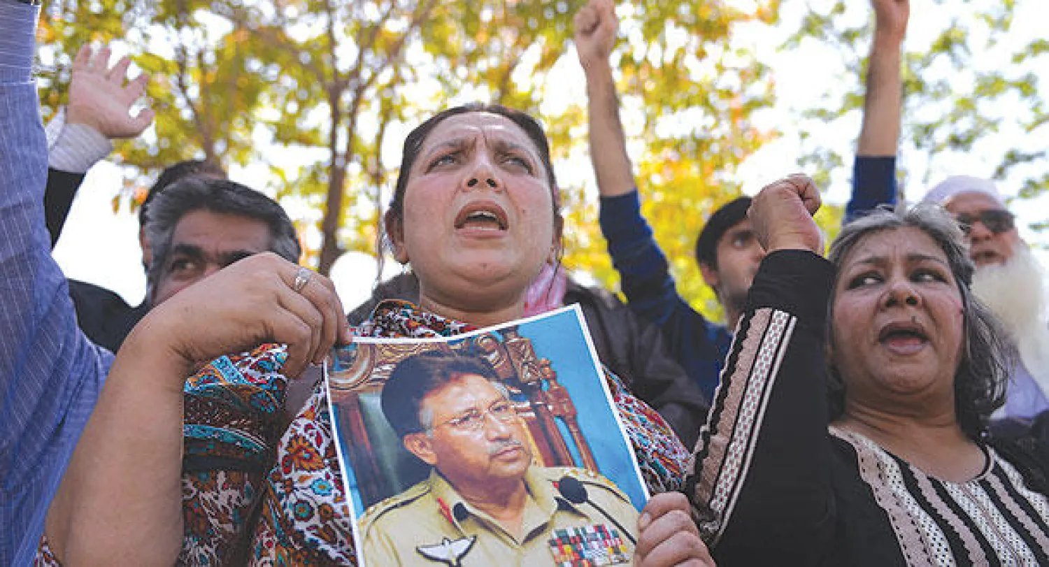 أنصار الرئيس السابق برويز مشرف المتهم بالخيانة العظمى وتظهر باكستانية ترفع  صورته أمام المحكمة في العاصمة إسلام آباد أمس (أ.ف.ب)