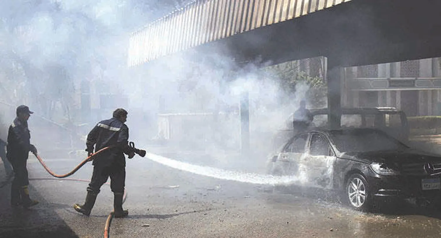 رجال الإطفاء يحاولون السيطرة على حريق في إحدى السيارات التي أضرم فيها طلاب النيران  داخل ساحة انتظار جامعة الأزهر أمس (أ.ب)