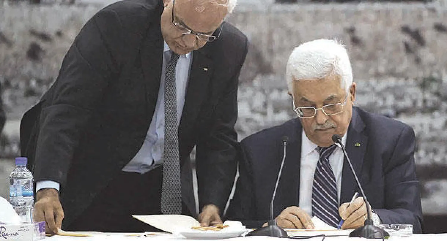 كبير المفاوضين الفلسطينيين صائب عريقات يساعد الرئيس محمود عباس على توقيع الانضمام  إلى 15 منظمة دولية في رام الله أمس (رويترز)