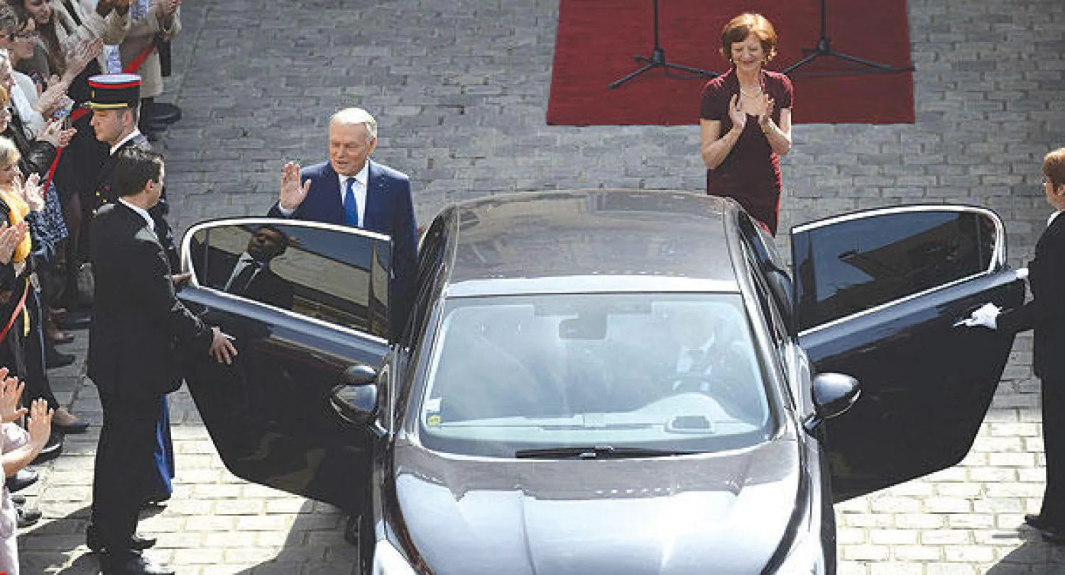 رئيس الوزراء الفرنسي المستقيل جان مارك أيرولت وزوجته بريجيت أثناء مغادرتهما فندق «ماتينيون»  بباريس بعد حفل التسلم والتسليم أمس (أ.ف.ب)