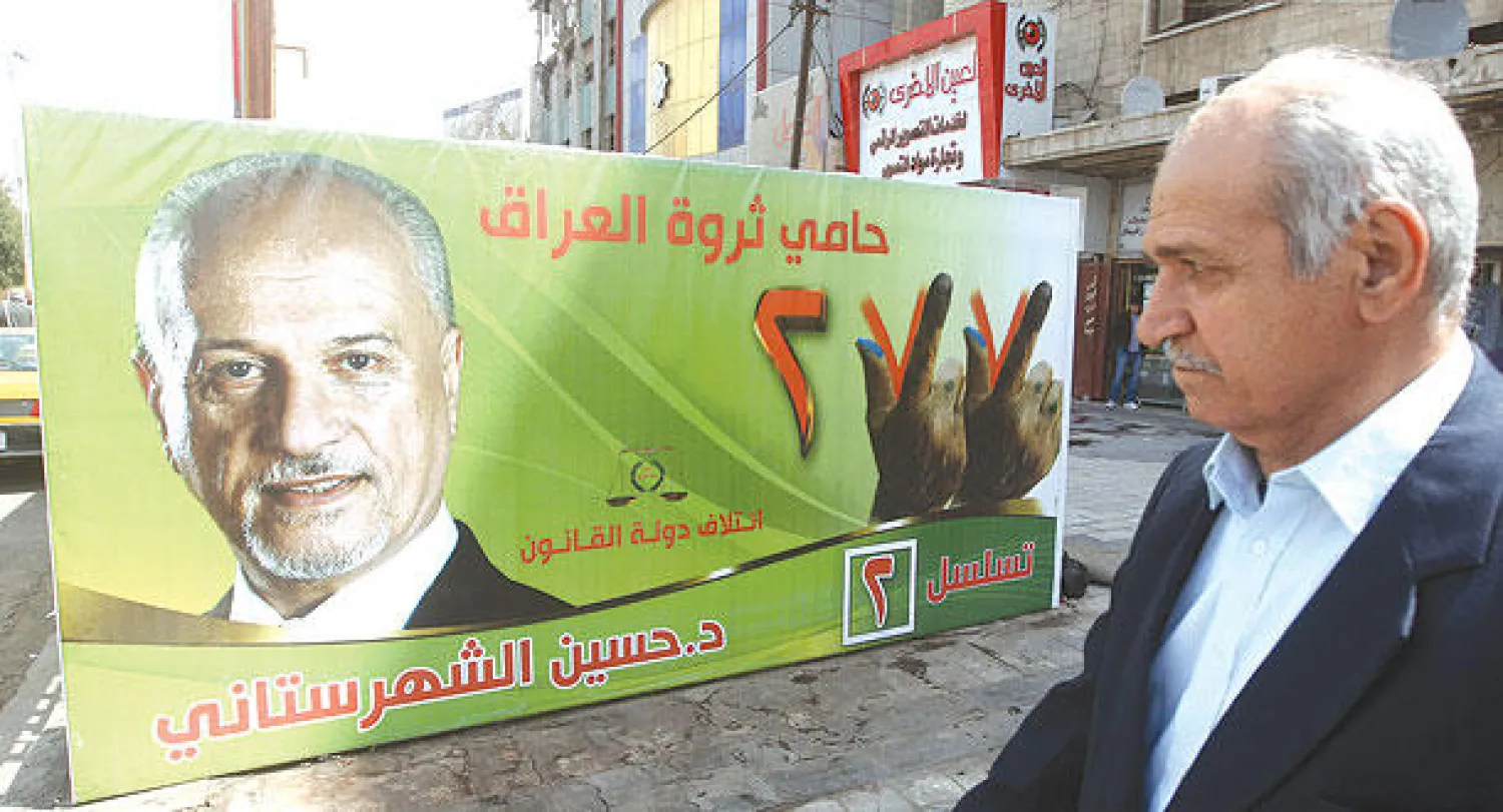 عراقي يتمعن ملصقا انتخابيا في بغداد أمس لنائب رئيس الوزراء لشؤون الطاقة حسين الشهرستاني يقدم نفسه فيه على أنه «حامي ثروة العراق» (أ.ف.ب)