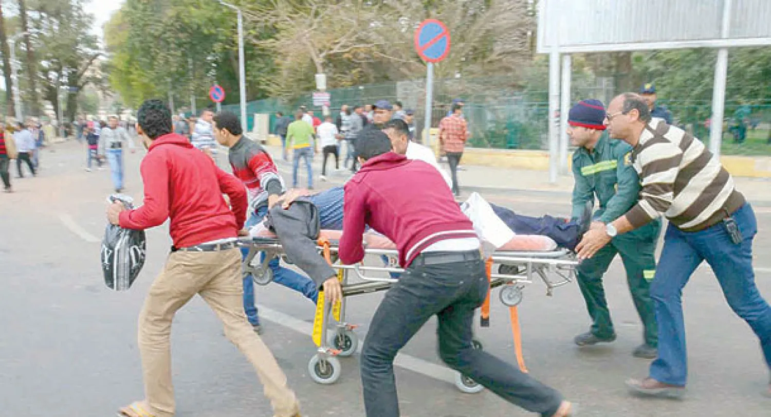 محاولات لإسعاف مصاب عقب سلسلة انفجارات في محيط جامعة القاهرة أمس  (إ.ب.أ)