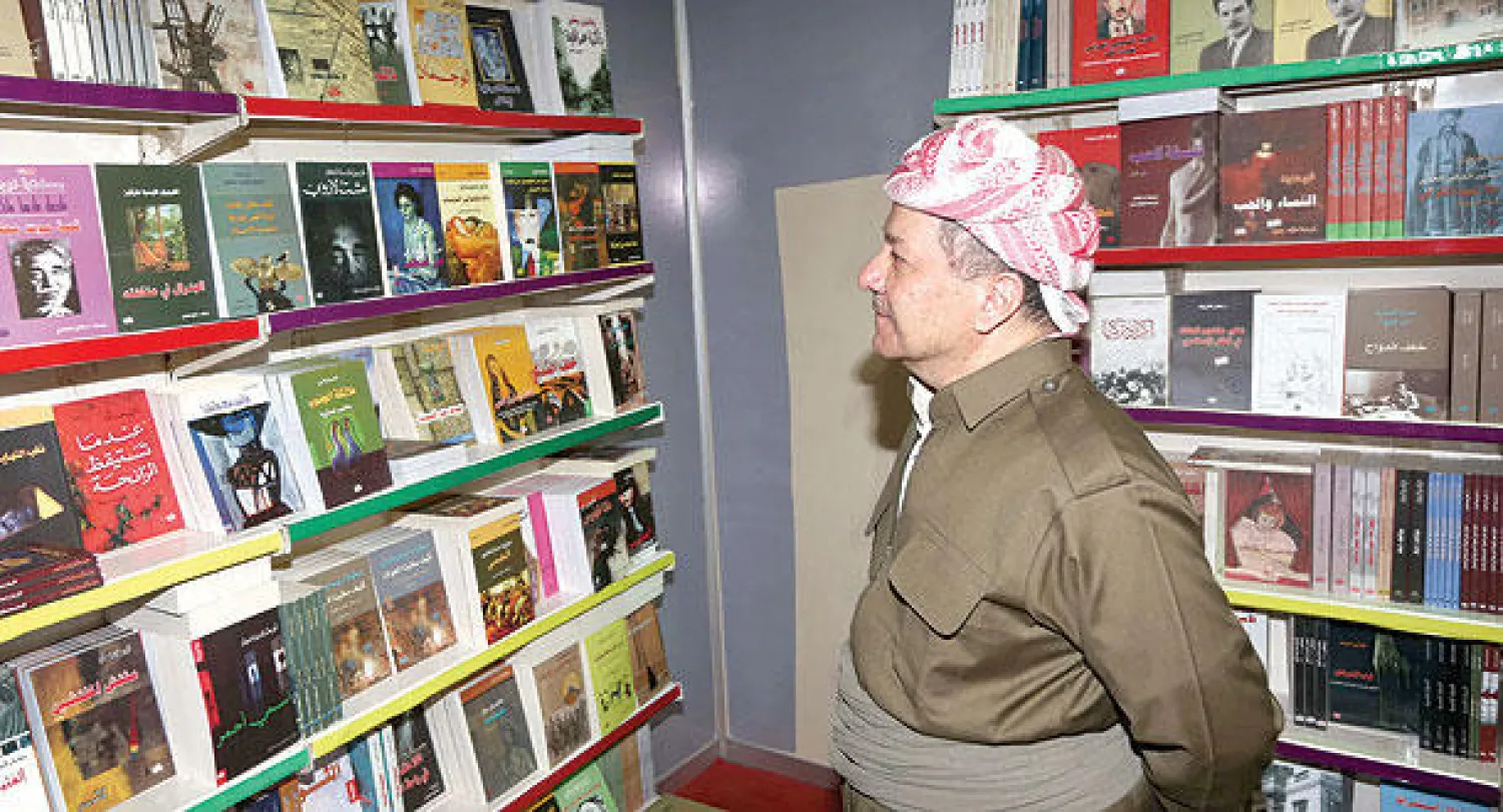 رئيس إقليم كردستان مسعود بارزاني يعاين كتبا بعد افتتاحه المعرض الدولي للكتاب في أربيل أمس (أ.ف.ب)
